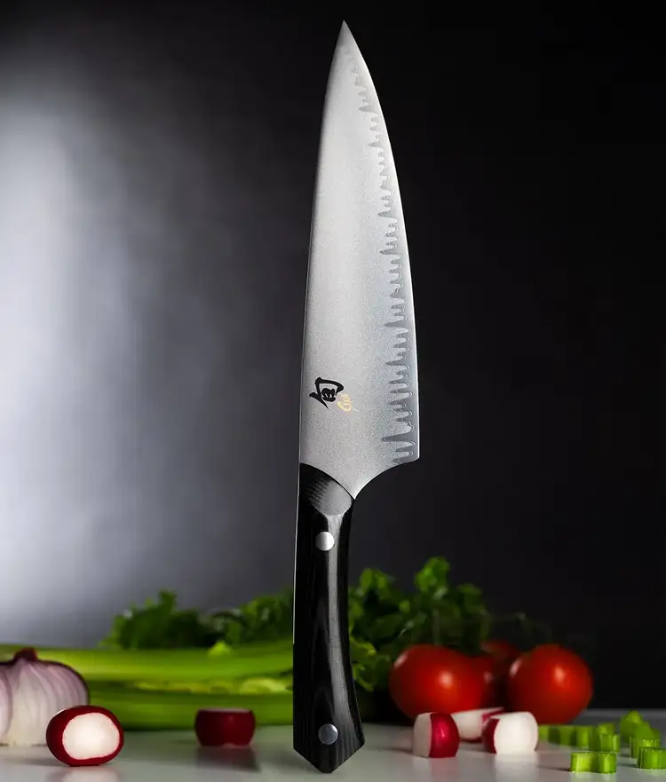 Narukami Chef's knife standing vertially on handle end with vegetables