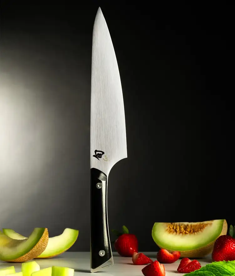 Kazahana Chef's knife standing vetically on handle end with vegetables