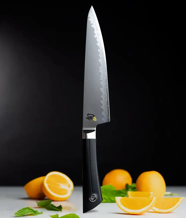 Sora Chefs knife standing vertically on handle end with vegetables and fruit