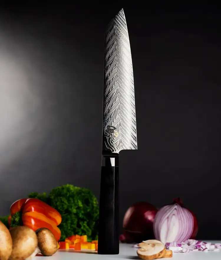 Dual Core Kiritsuke standing veticall on handle end with vegetables