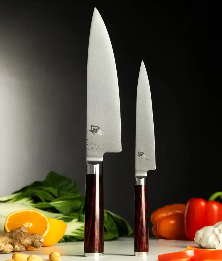 Two Kohen knives standing vertically on end cap with vegetables