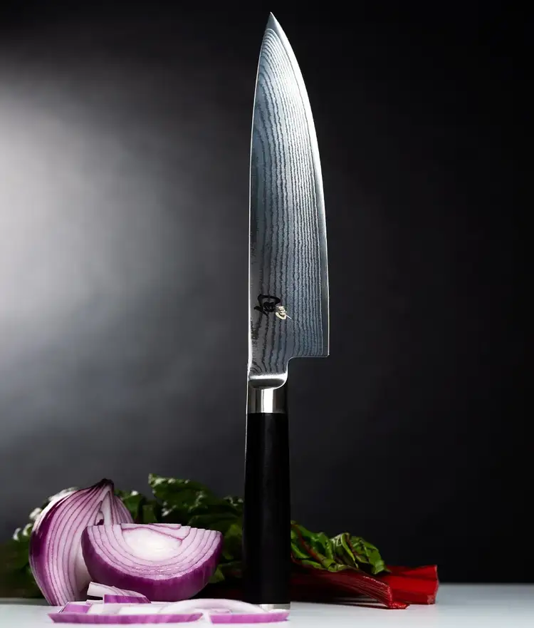 Classic Chefs knife standing vertically on end cap with vegetables