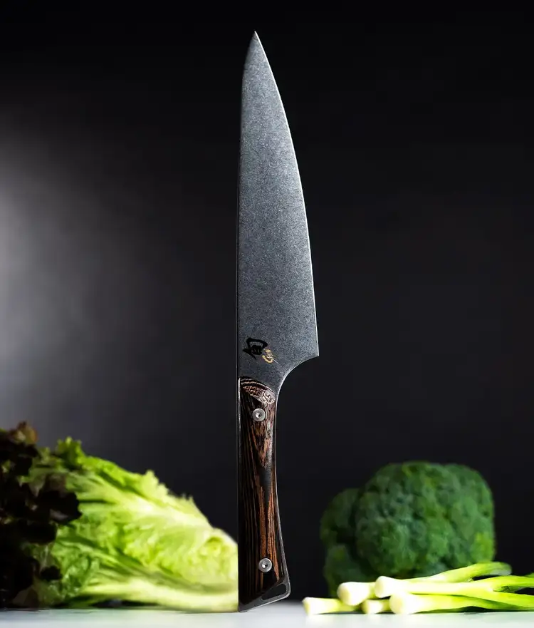 KansoChef's knife standing vertially on handle end with vegetables